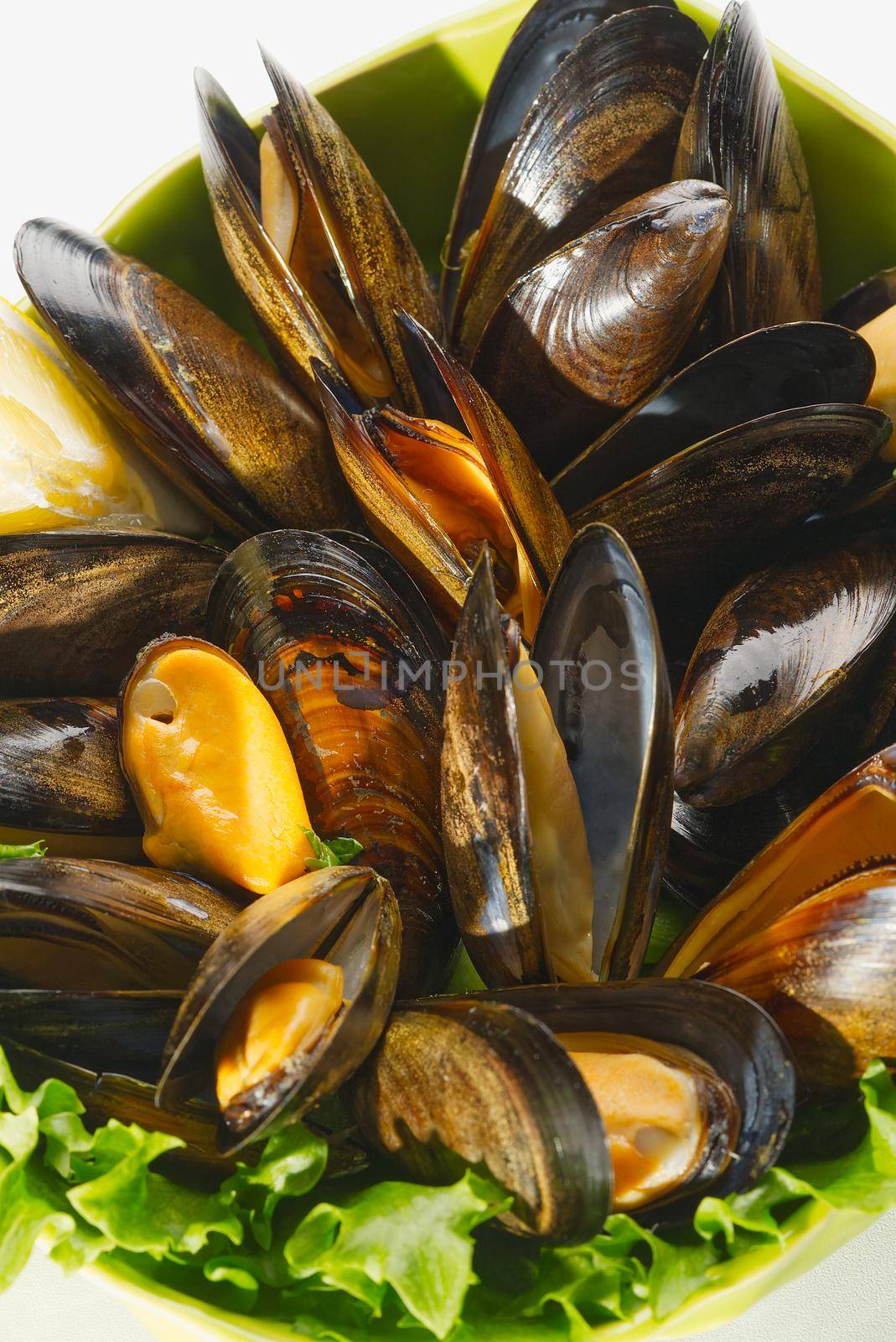 Cooked mussels with lemon and parsley on table. served mussels ready to eat by PhotoTime