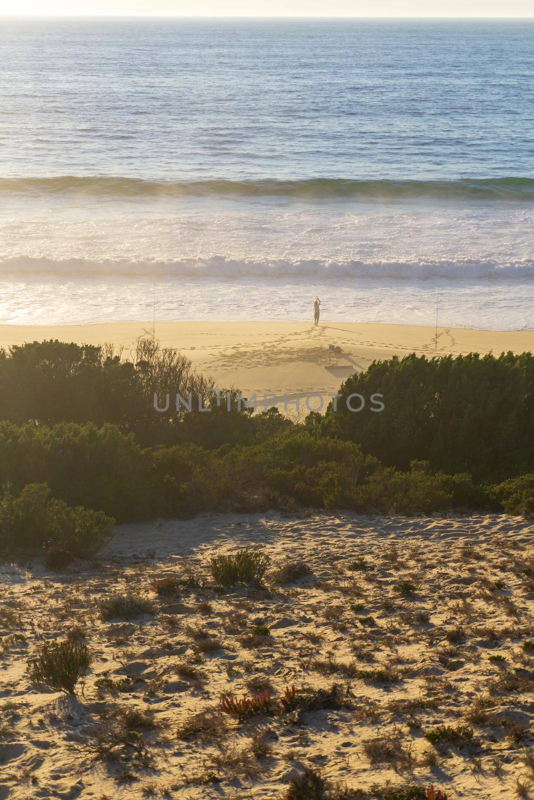 Ocean beach with a lone figure of a fisherman on the shore