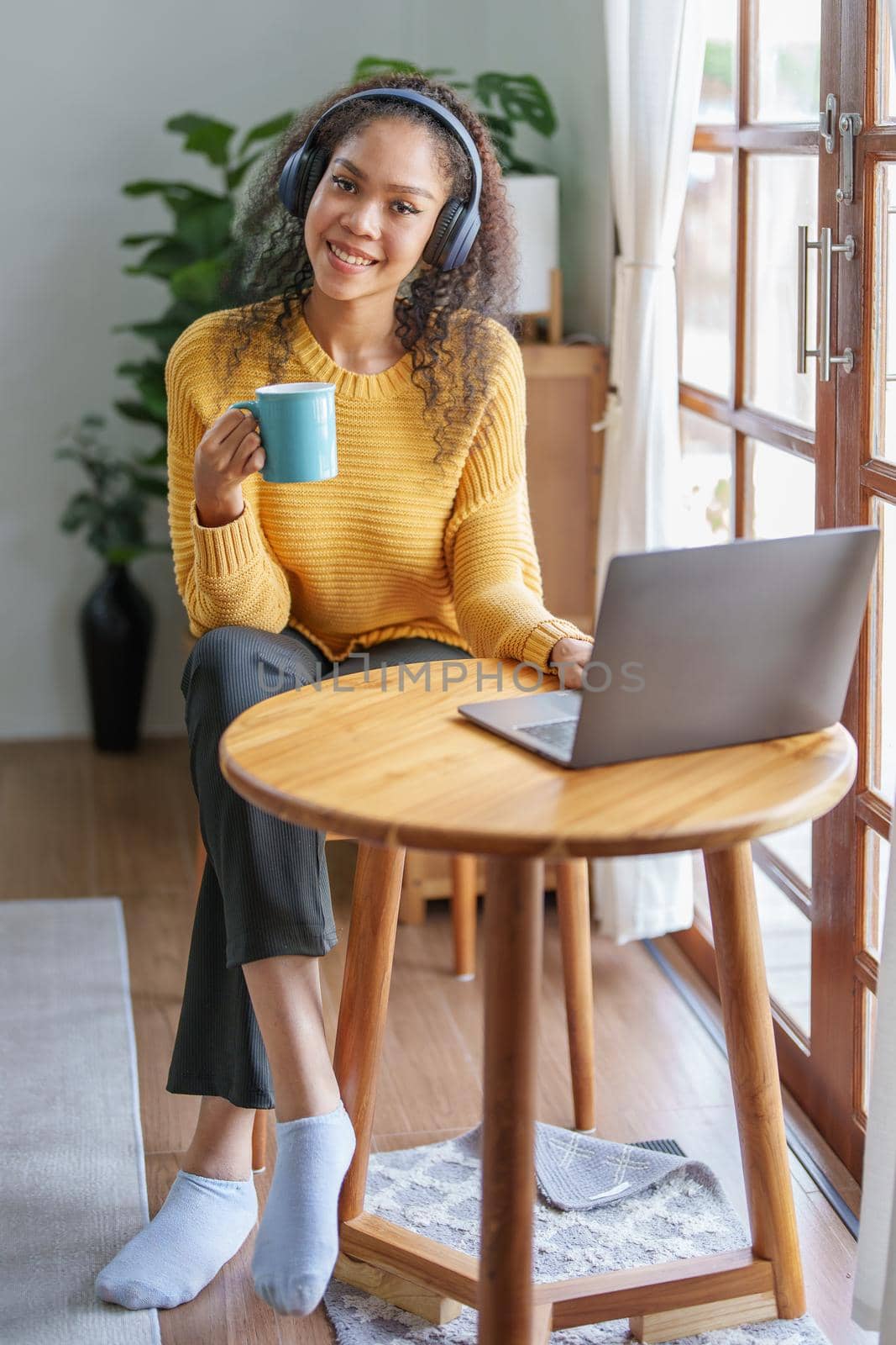 Portrait of an African American wearing headphones holding a coffee cup and using a computer by Manastrong