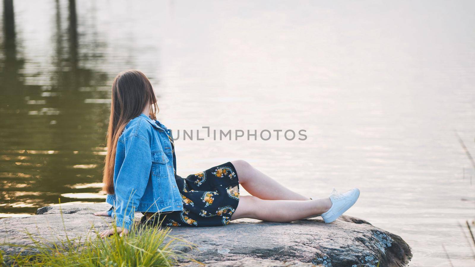 A girl sits by the lake on a rock