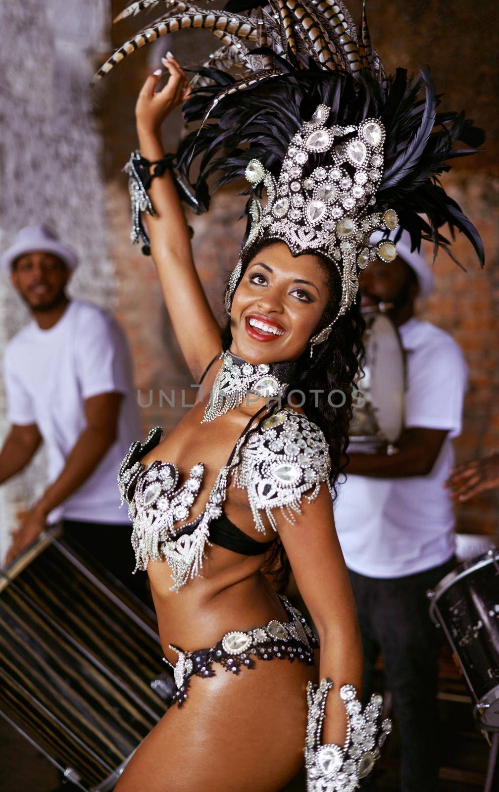 Shes got flare. an attractive ethnic female in a beaded costume dancing the samba with her band members. by YuriArcurs