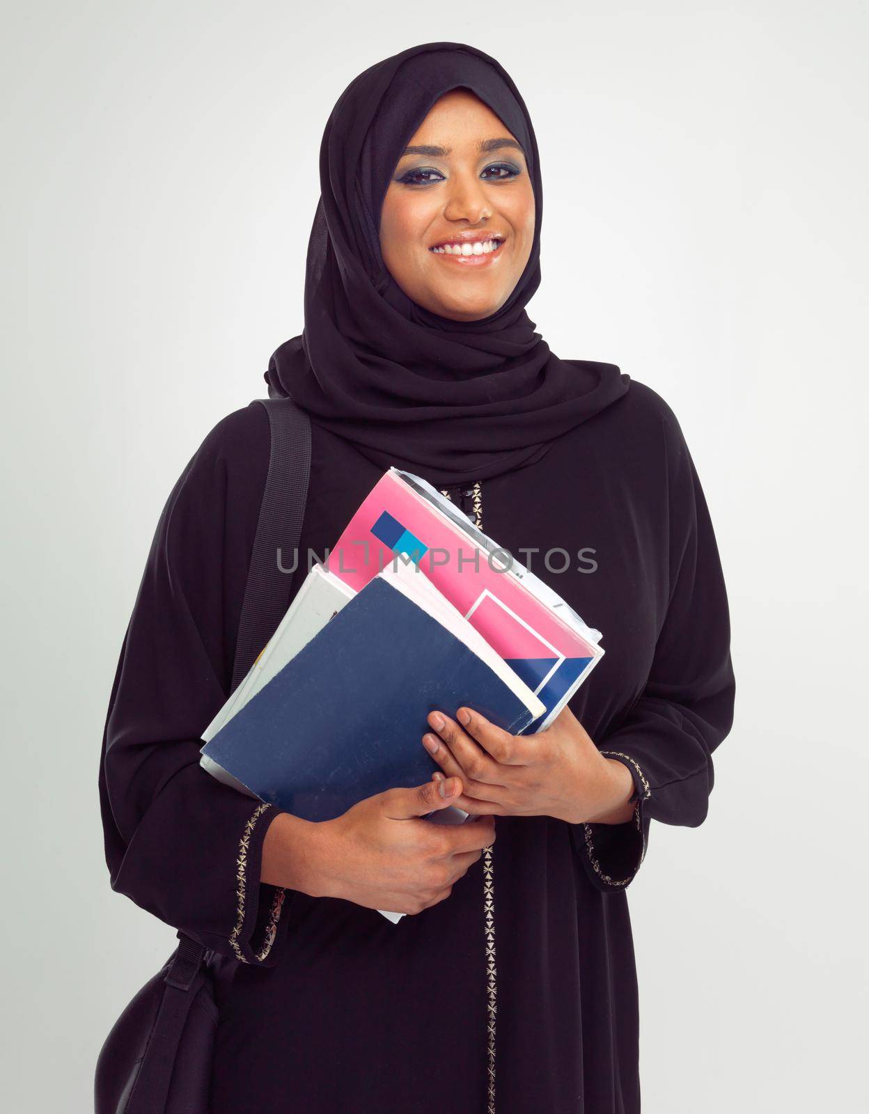 Shes an A student. Portrait of a young muslim woman wearing a burqa holding documents. by YuriArcurs