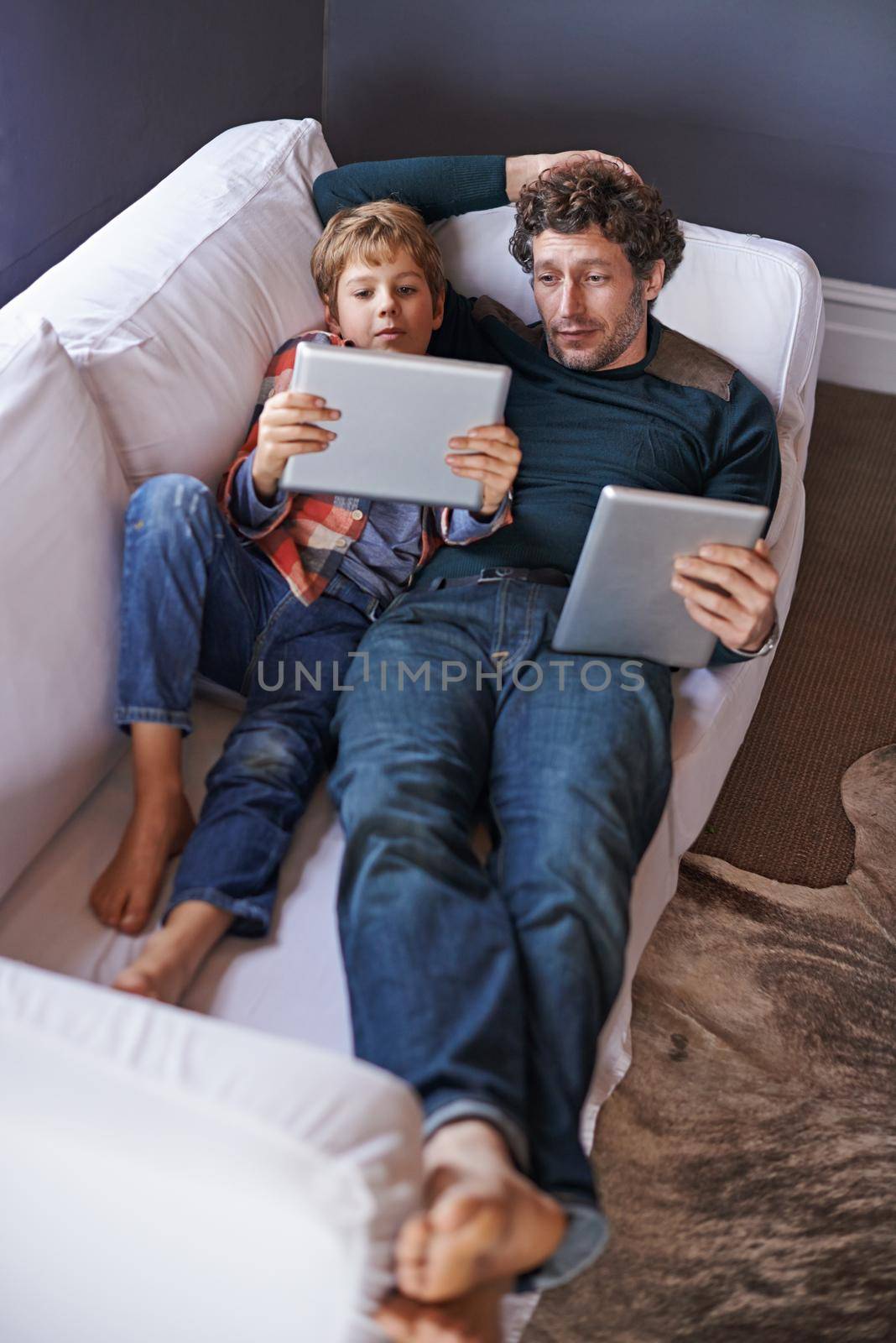 Laid-back browsing together. a father son lying on the couch together while using digital tablets