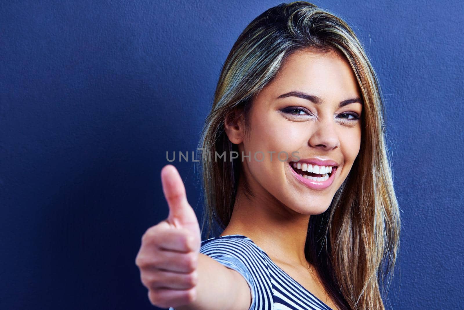 I approve this message. Cropped portrait of a happy young woman giving a thumbs up. by YuriArcurs