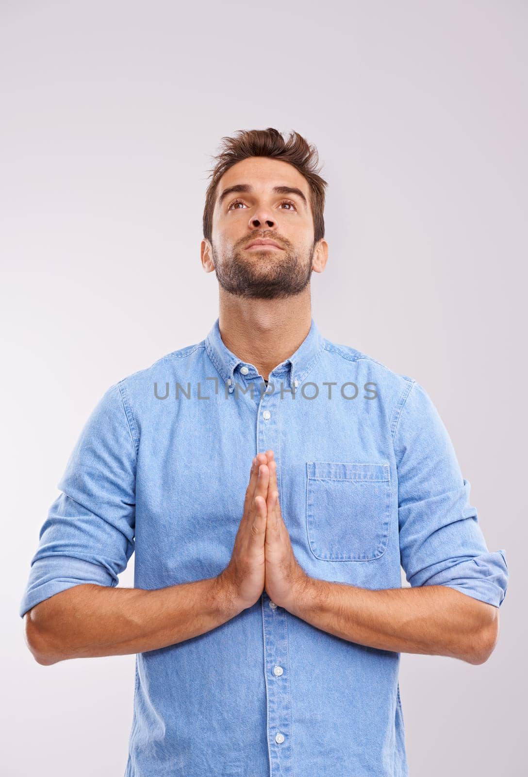 God, please answer me. Studio shot of a handsome young man praying against a gray background. by YuriArcurs