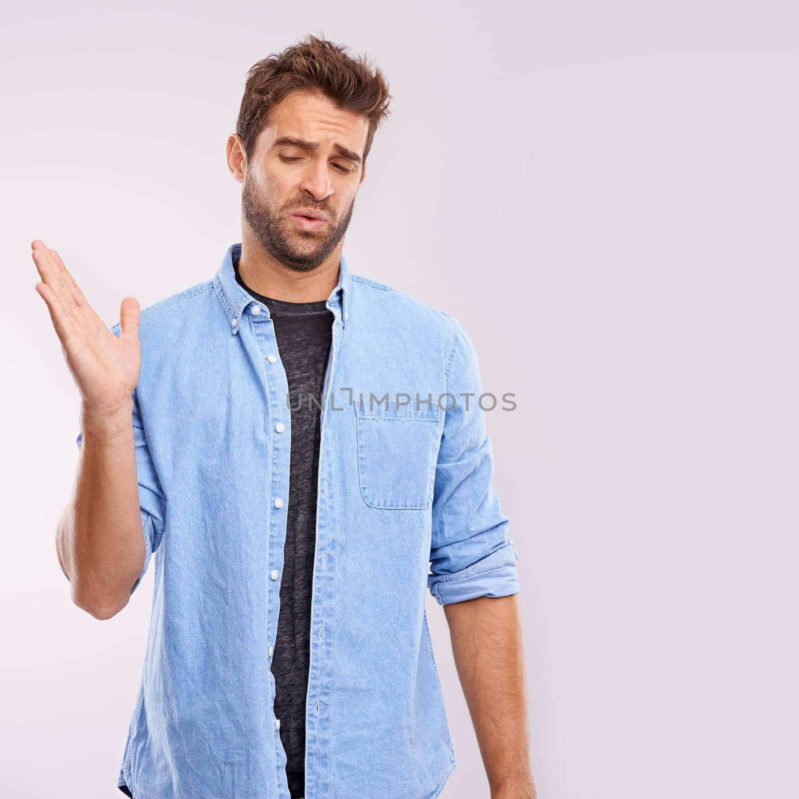 Theres no hiding his feelings. Studio shot of a handsome young man waving his hands in gesture after smelling something unpleasant