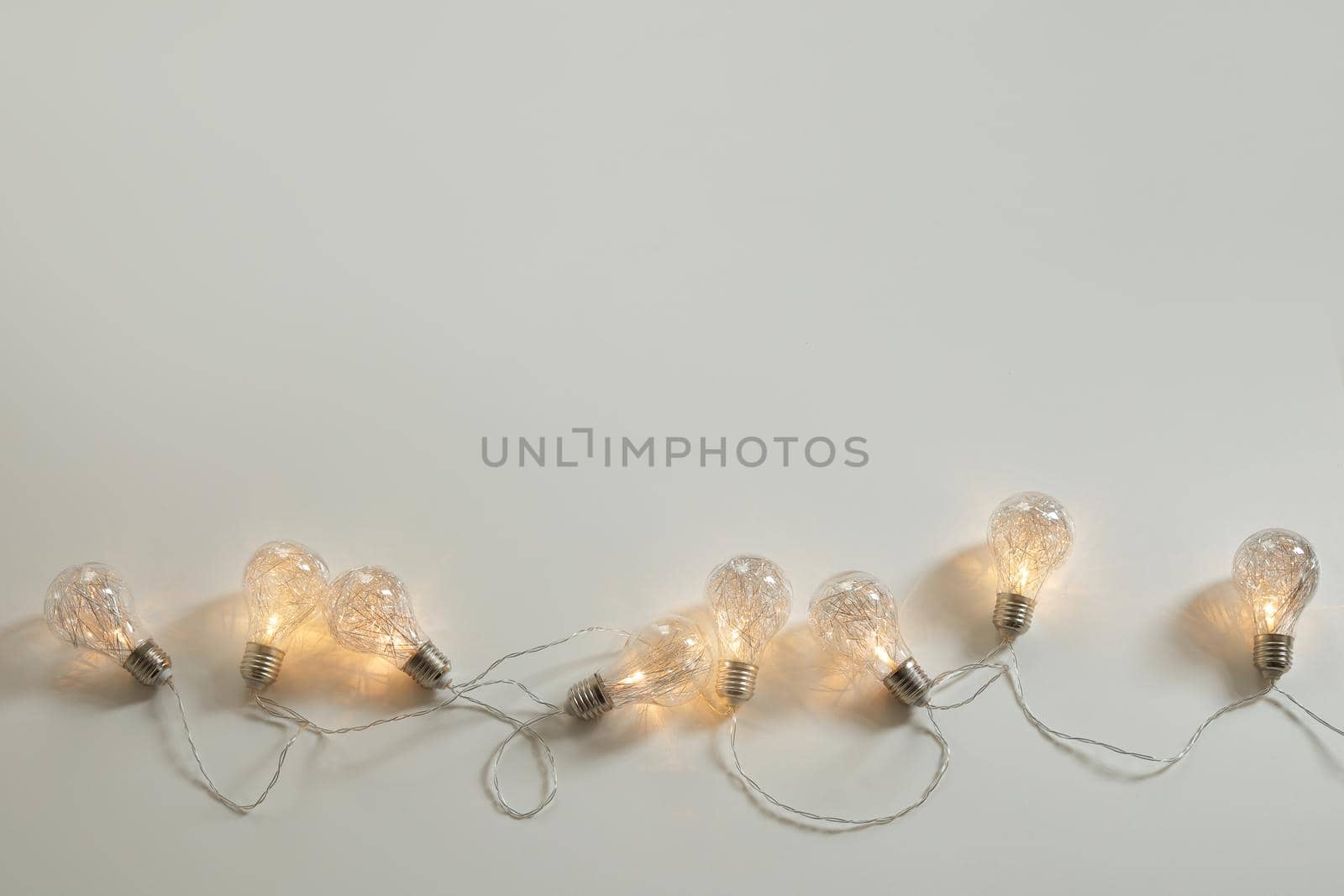 Christmas background. Fairy lights on the white background. Free space for text, copy space. Flat lay, top view.
