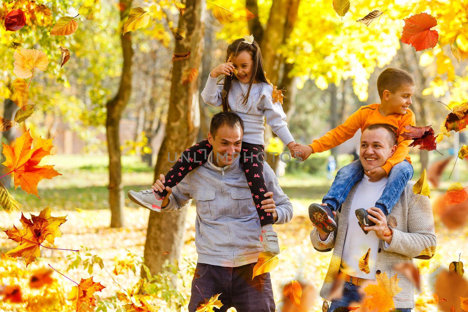 family walking in an autumn park with fallen fall leaves. High quality photo