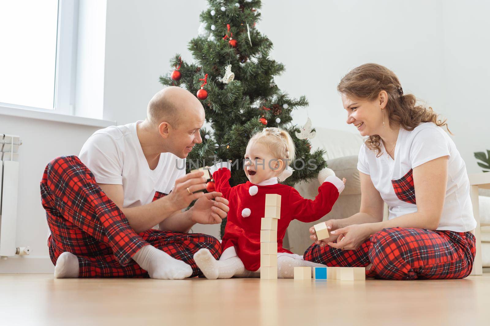 Baby child with hearing aid and cochlear implant having fun with parents in christmas room. Deaf , diversity and health and diversity by Satura86