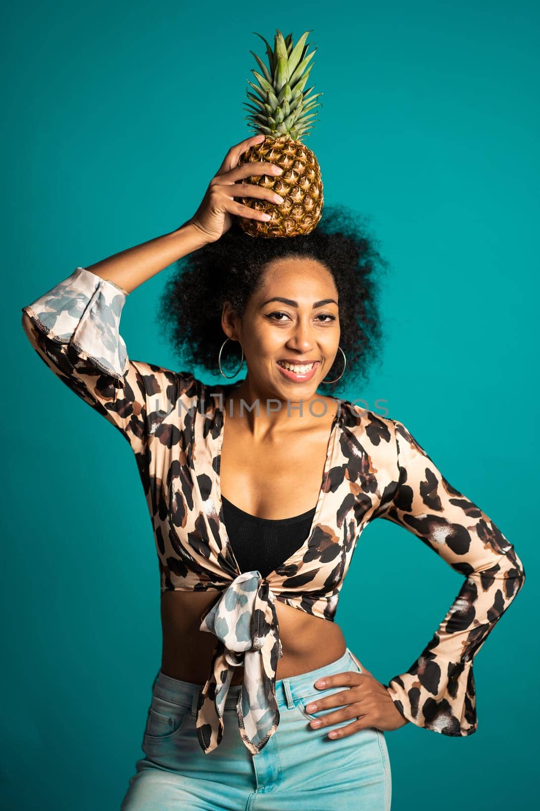 Playful young african american woman with fresh pineapple on head as crown. Healthy exotic lifestyle and eating concept. High quality photo