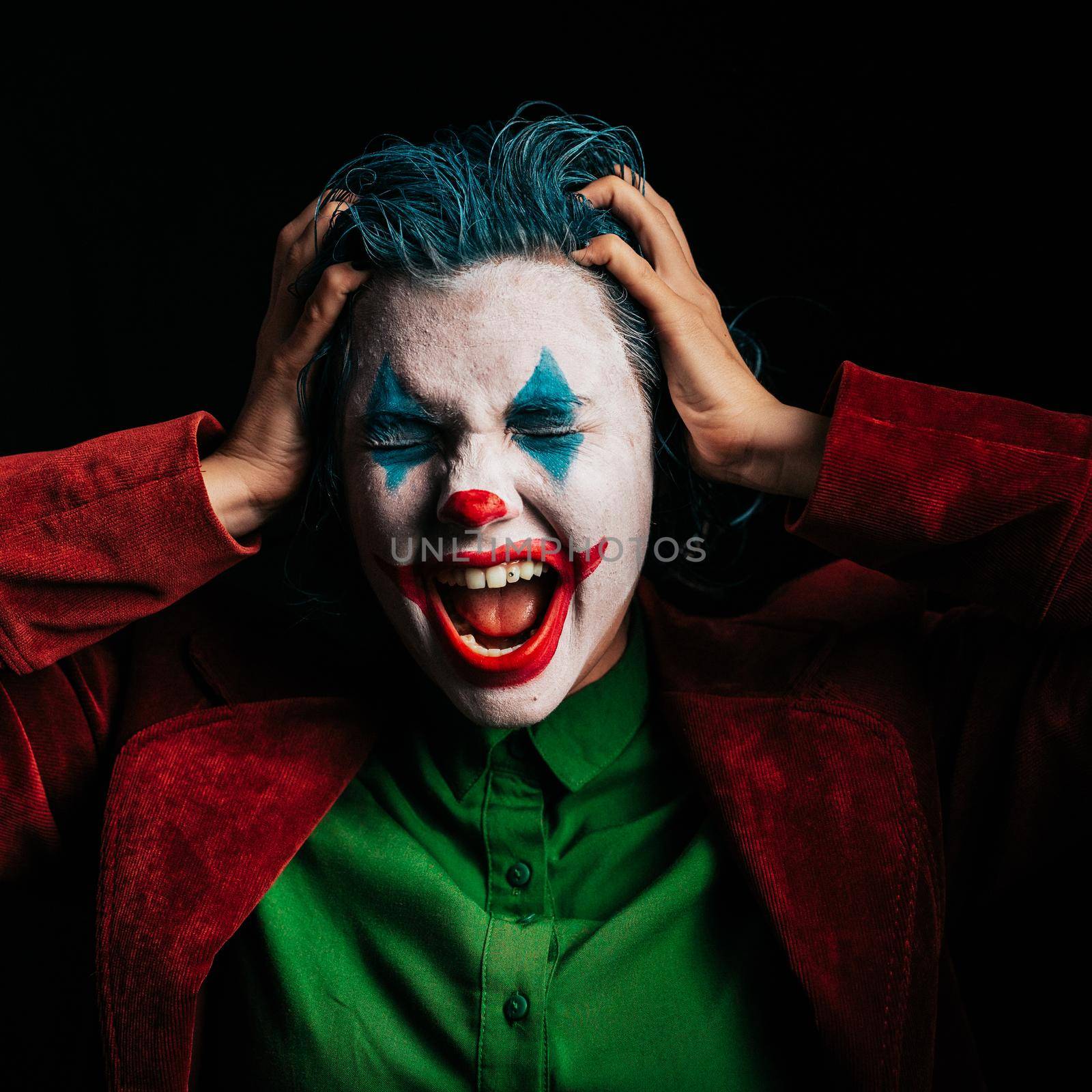 Make-up Joker with green hair for Halloween. Close-up screaming face on black background. by kristina_kokhanova