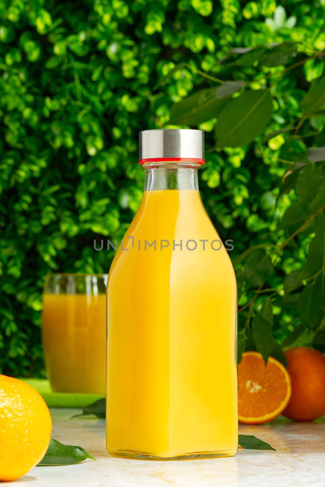 bottle of fresh orange juice with fresh fruits over a green background. fresh orange juice