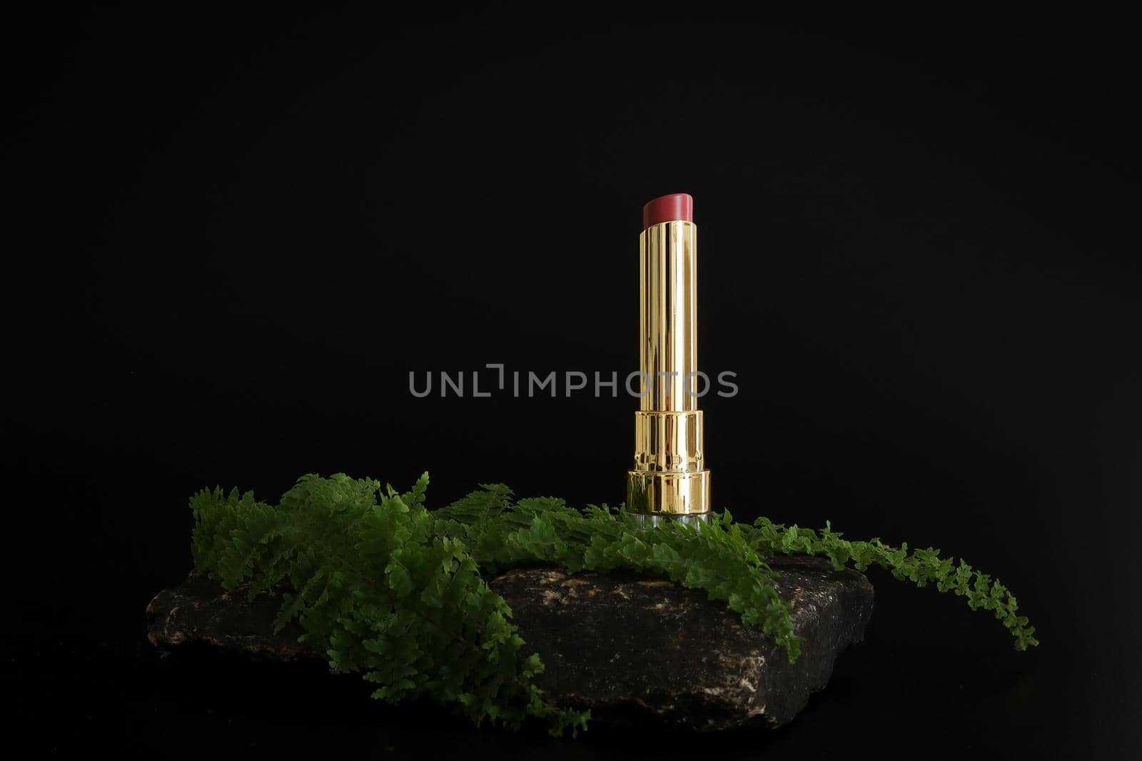 Lipstick standing on stone podium. Lipstick presentation on the black background. by creativebird