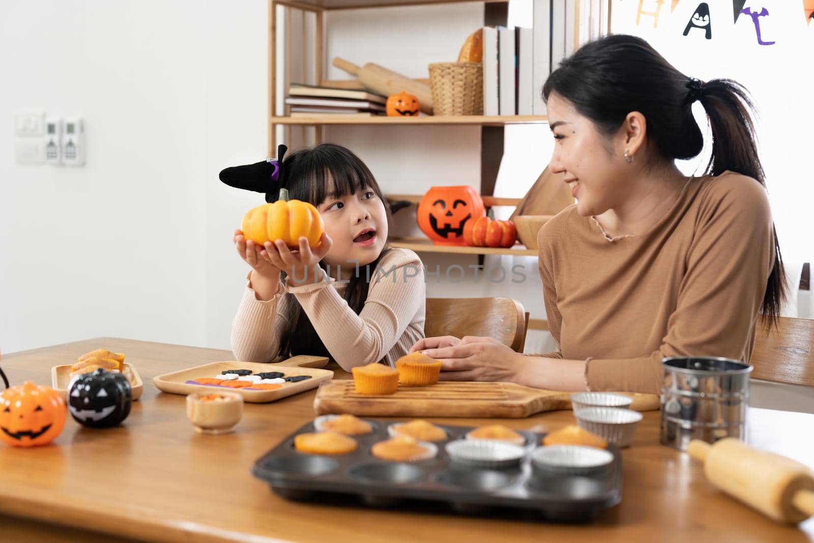 Mother and her daughter having fun at home. Happy Family preparing for Halloween. Mum and child cooking festive fare in the kitchen. by nateemee