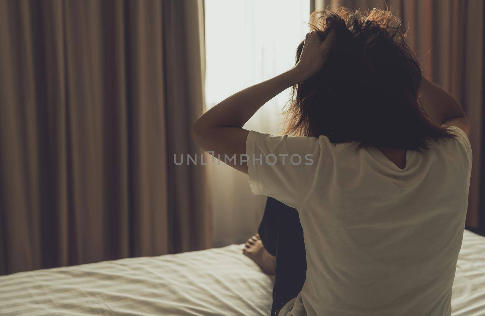 World Mental Health Day concept. Rear view of angry woman put hand on head and pulling hair. Mental illness woman sit on bed in bedroom. Woman with mental health problems. Stressed and nervous person. by Fahroni