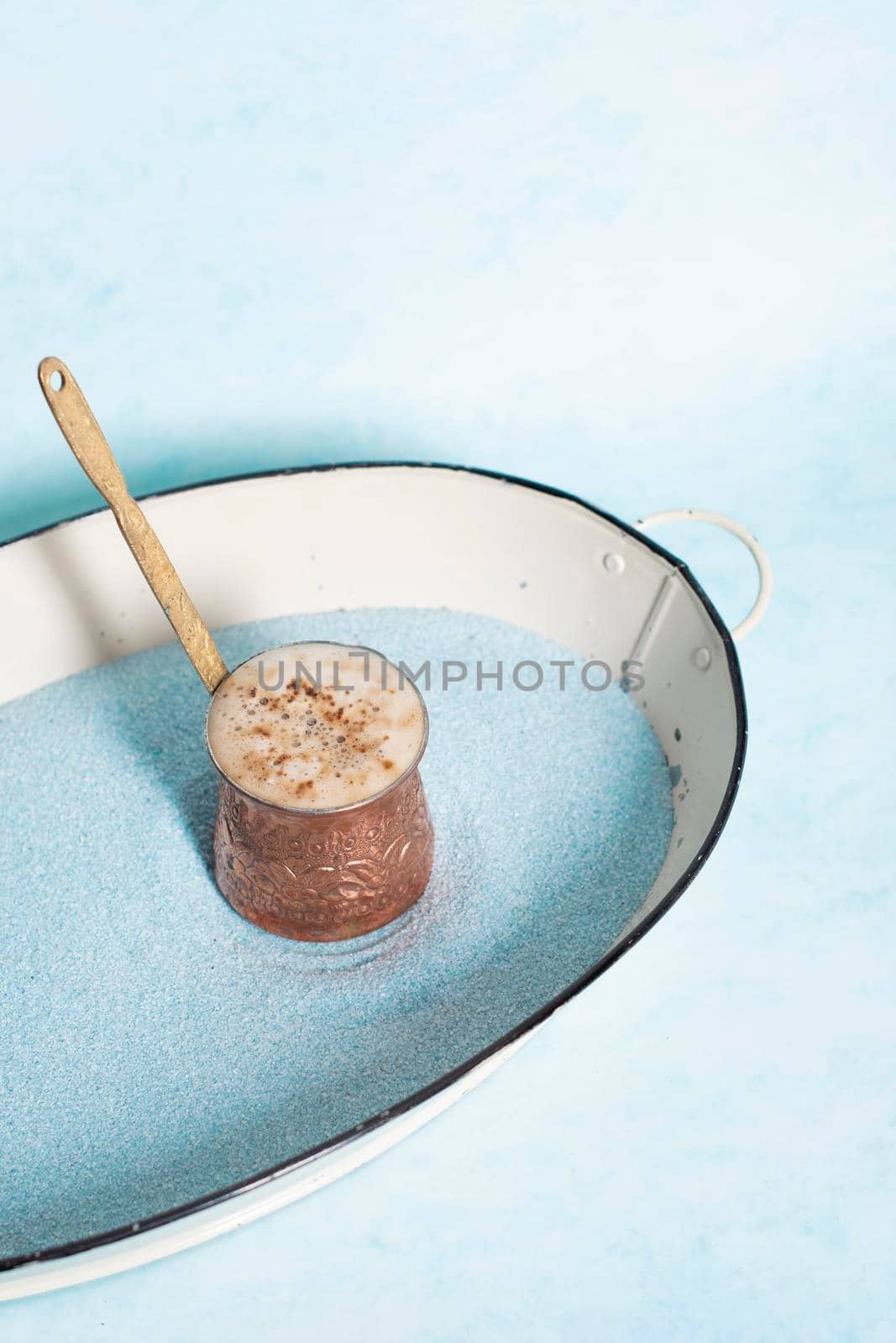 copper coffee pot with hot coffee on blue sand and blue background, beautiful blue color, coffee break, turkish coffee. High quality photo