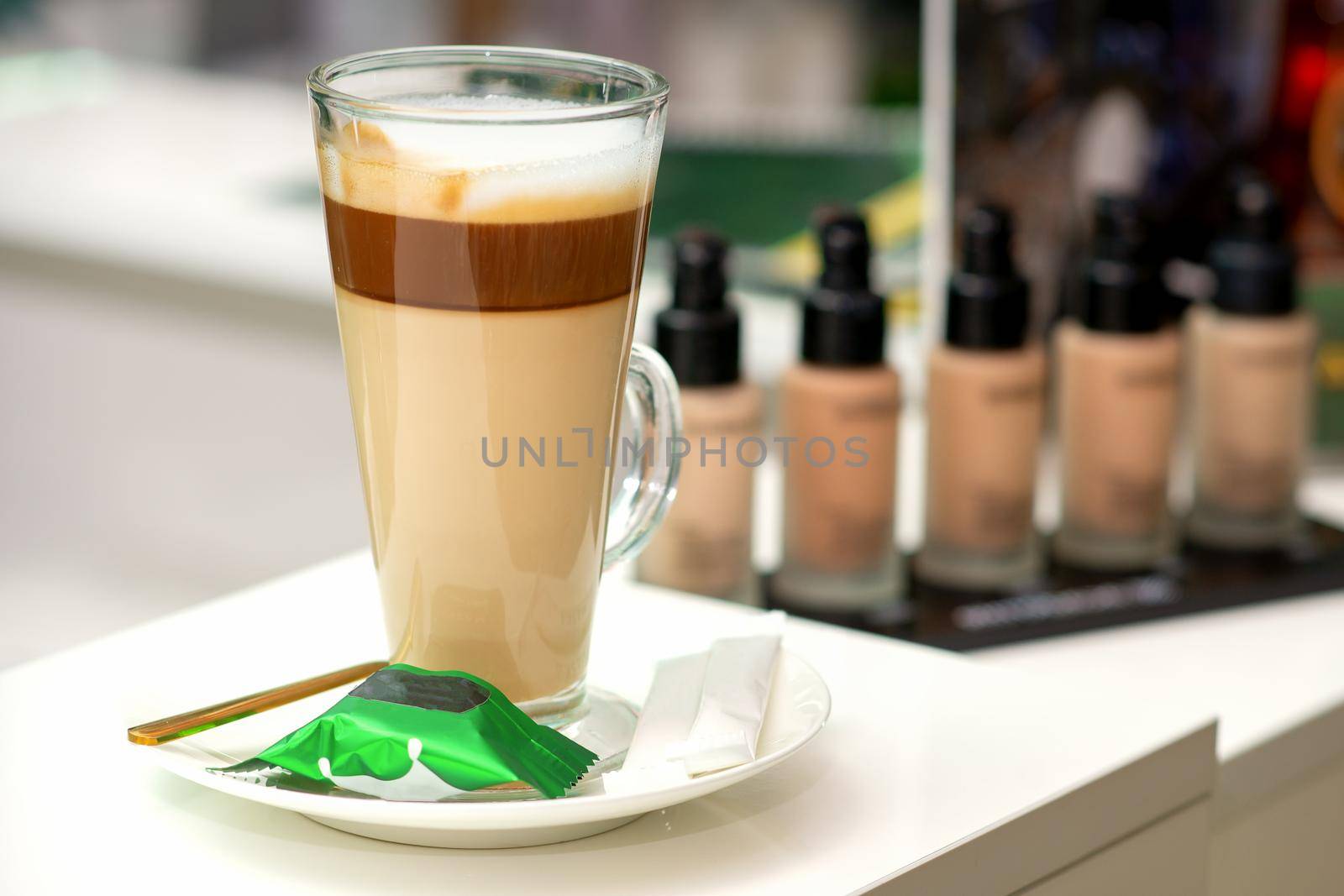 A cup of latte with candy on a saucer on the table in the manicure room. Manicure master place