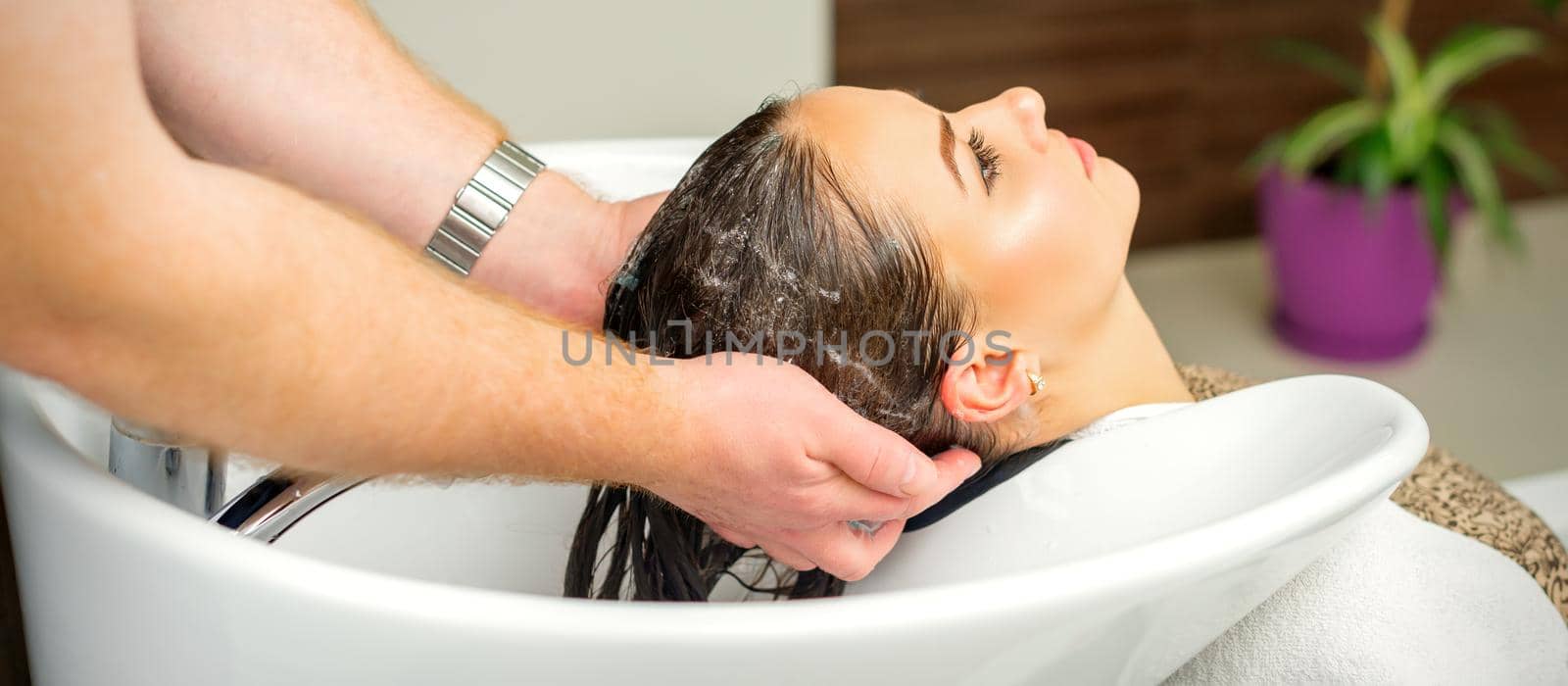 Beautiful caucasian woman washing hair in a beauty salon. by okskukuruza