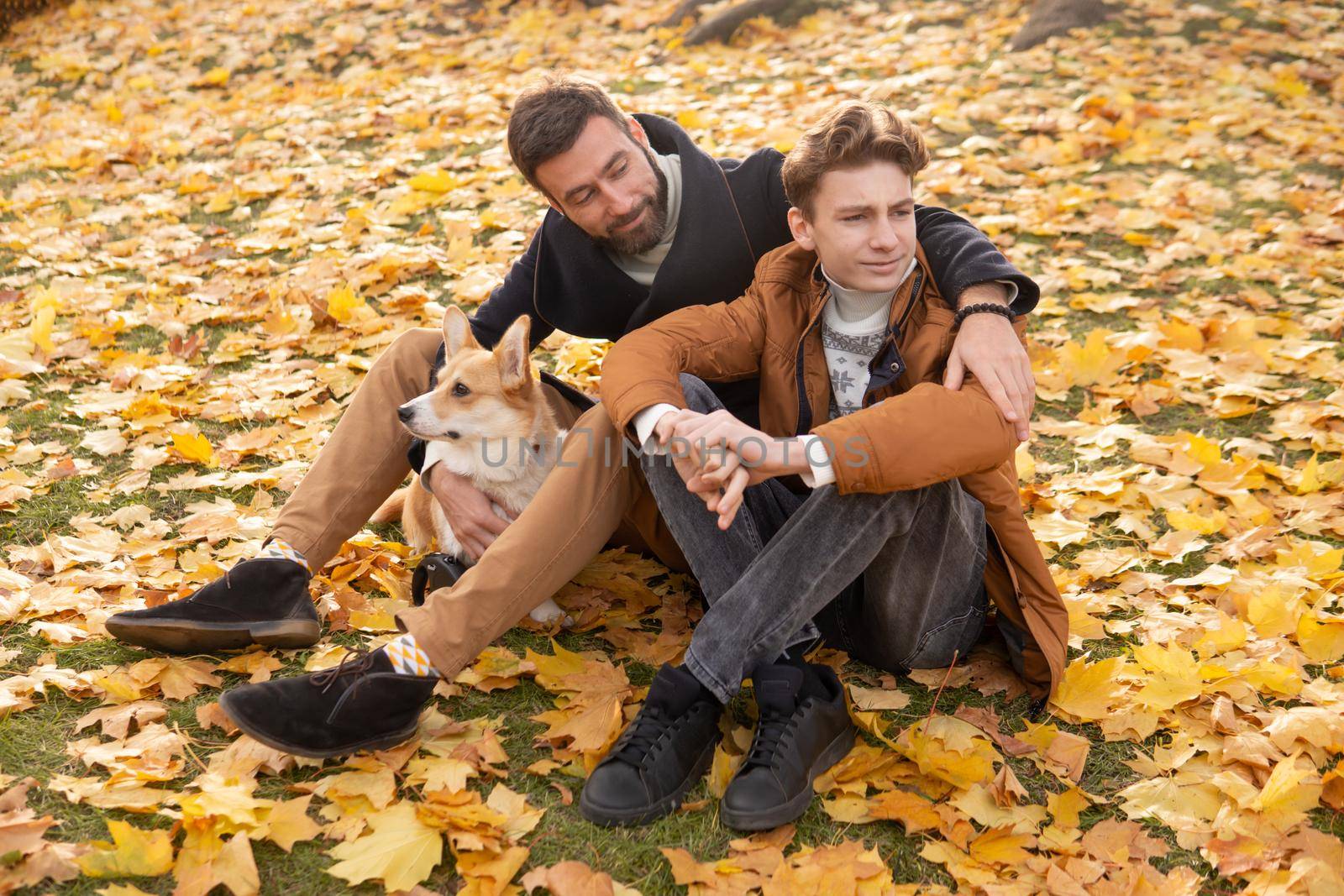 Father and son with a pet on a walk in the autumn park.