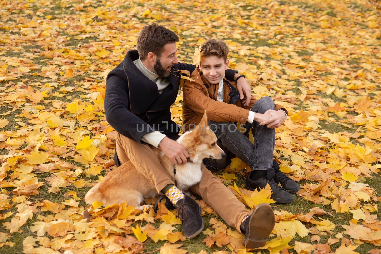 Father and son with a pet on a walk in the autumn park.