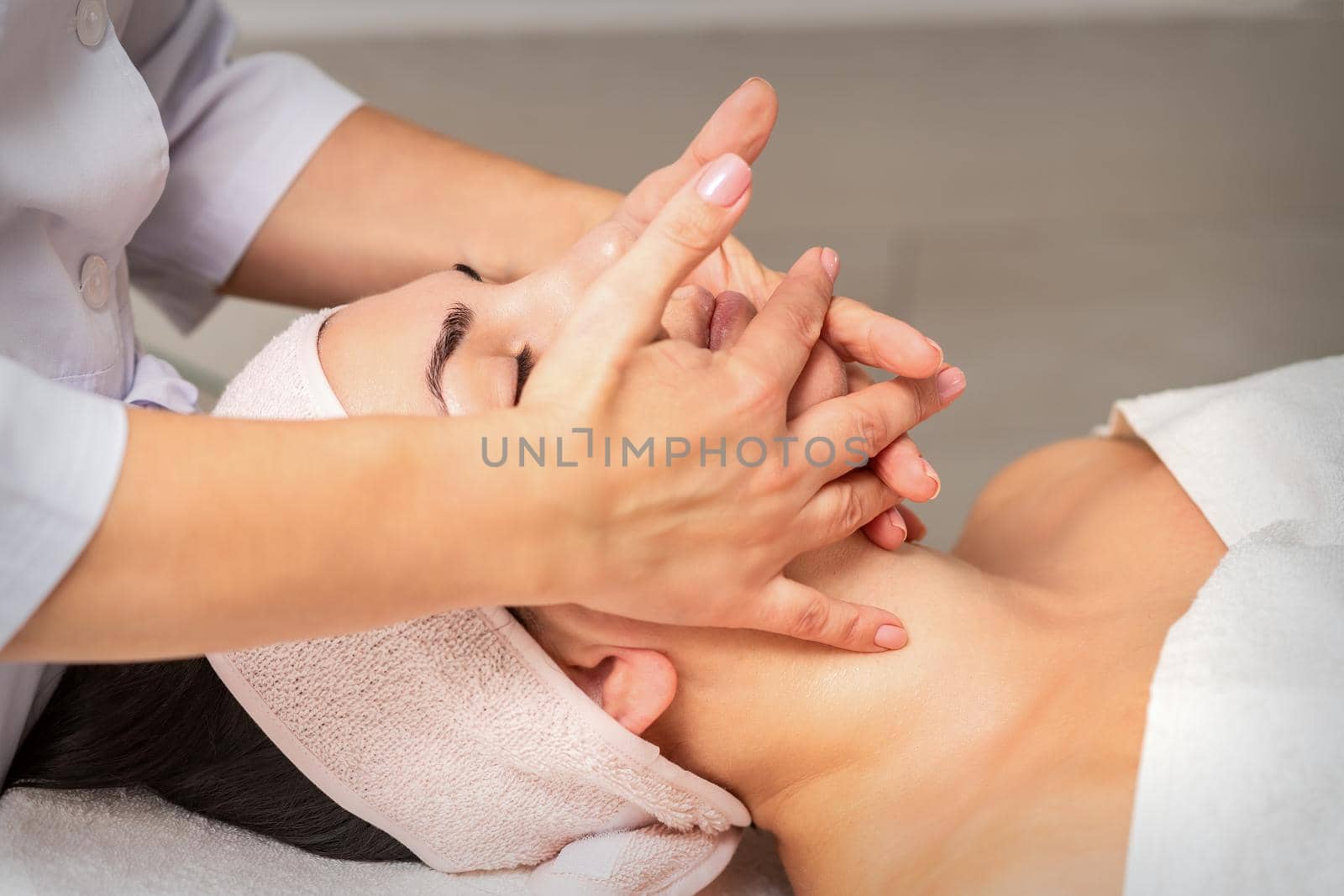 Beautiful caucasian young woman getting a facial massage at a beauty salon