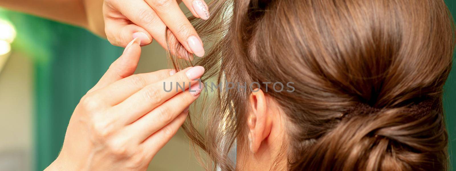 Close Up hairdresser stylist makes hairstyle for a young woman in a beauty salon