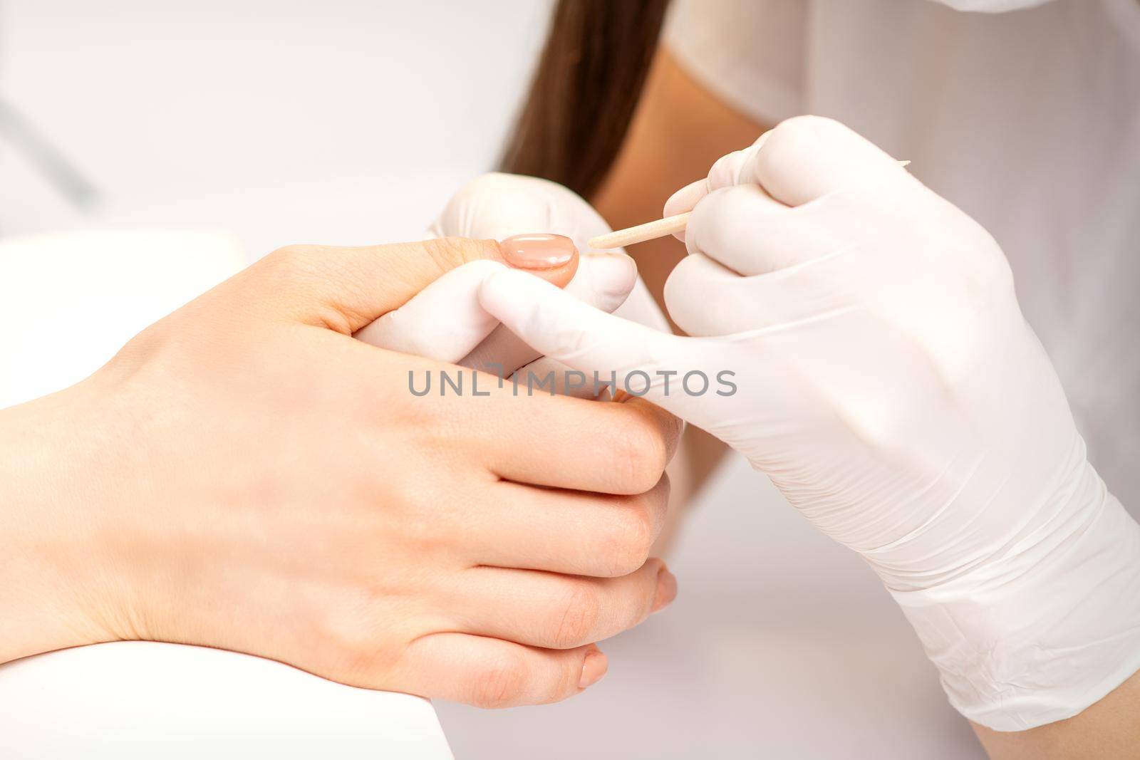 Young woman receiving pink or beige nail polish in a beauty salon