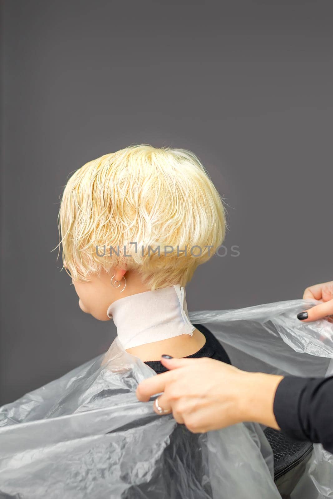 Hairstylist covers neck with cape for a female client in a beauty salon