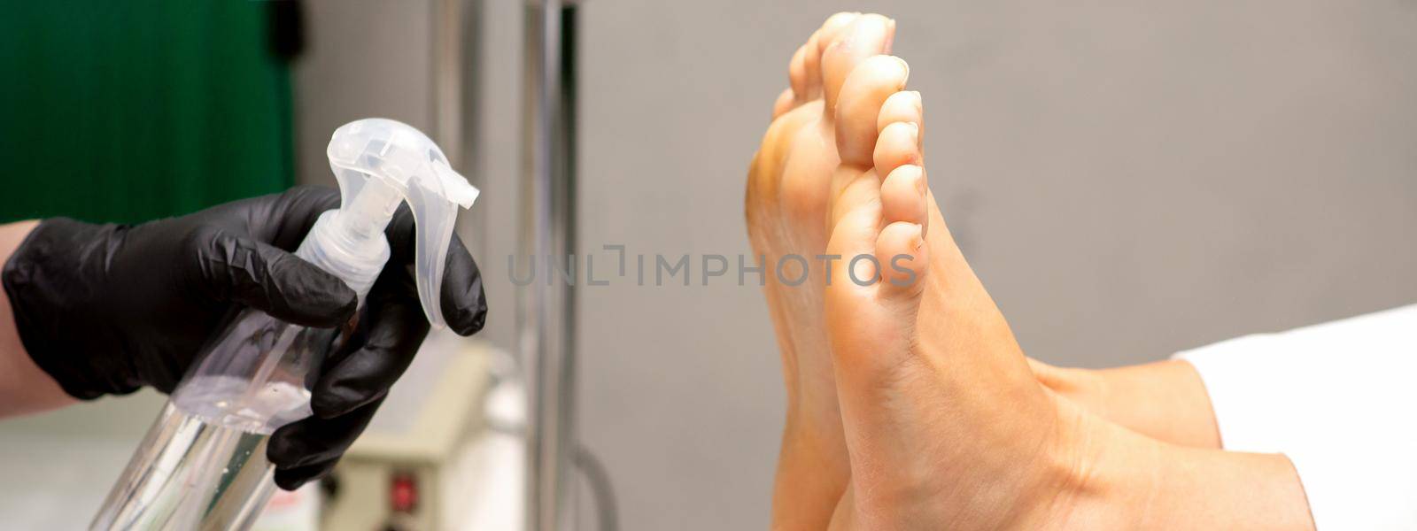 Pedicure master disinfects the feet of woman with the preparation decontamination in beauty salon. by okskukuruza