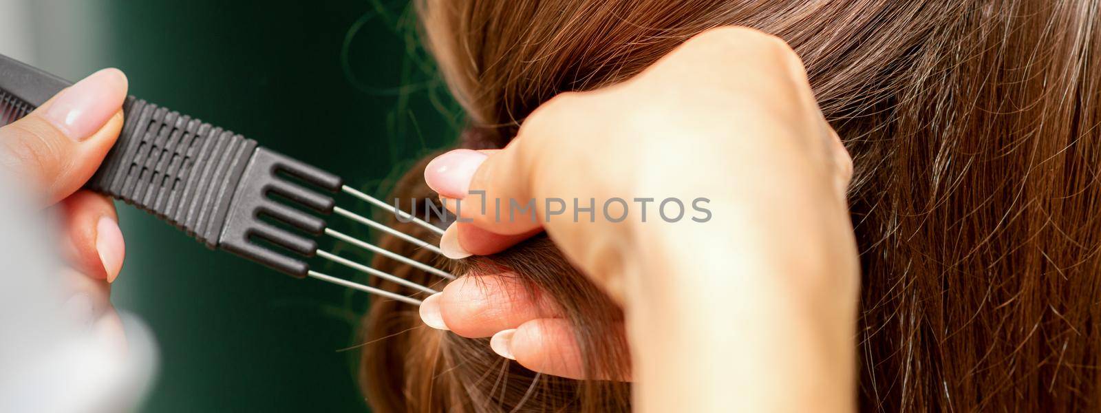 Close Up hairdresser stylist makes hairstyle for a young woman in a beauty salon. by okskukuruza