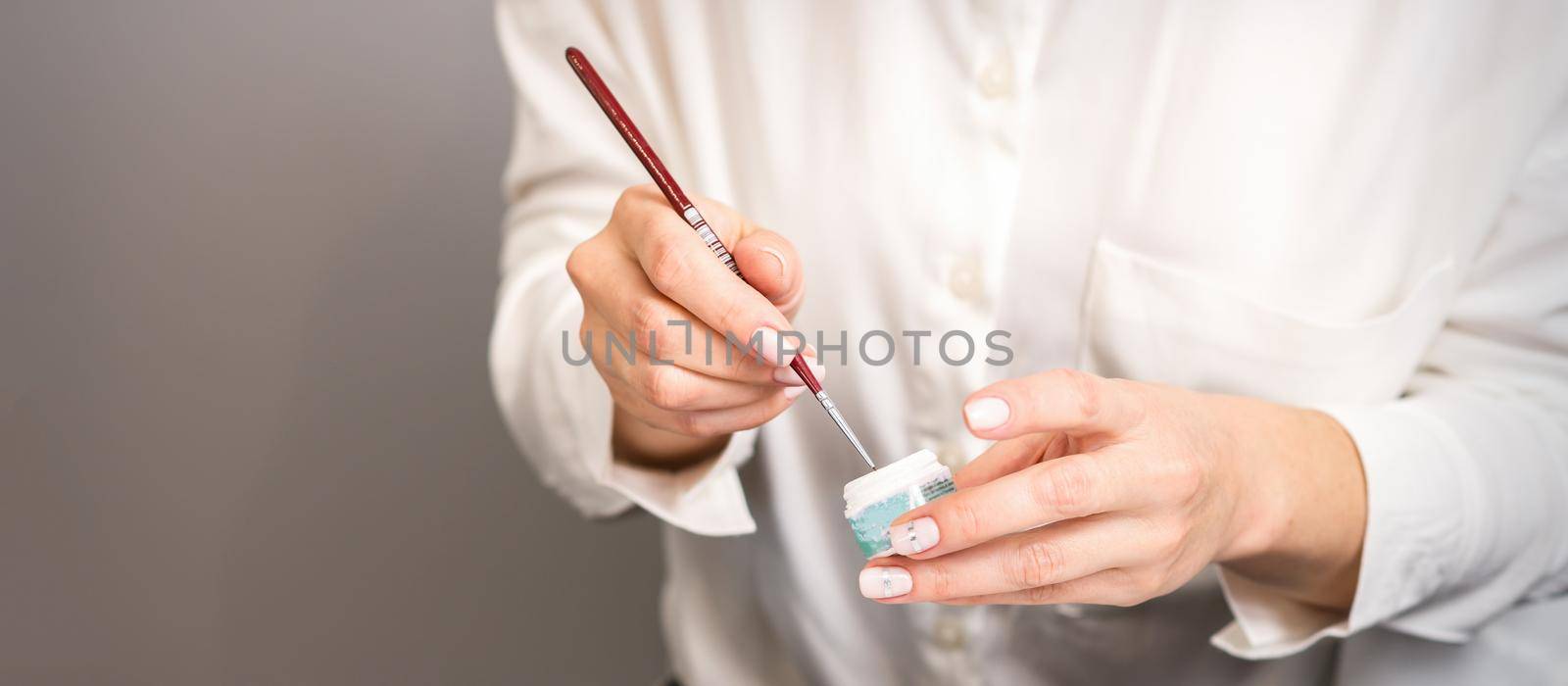 Blue glitter nail polish with a nail brush in hands of female manicurist