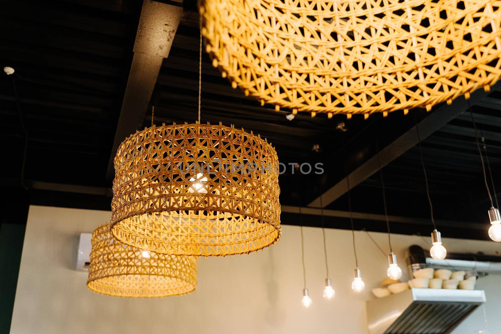 Beautiful interior of the confectionery studio. Cozy lamps in a coffee shop. Wicker lampshades on lamps in a cafe. Family bakery.