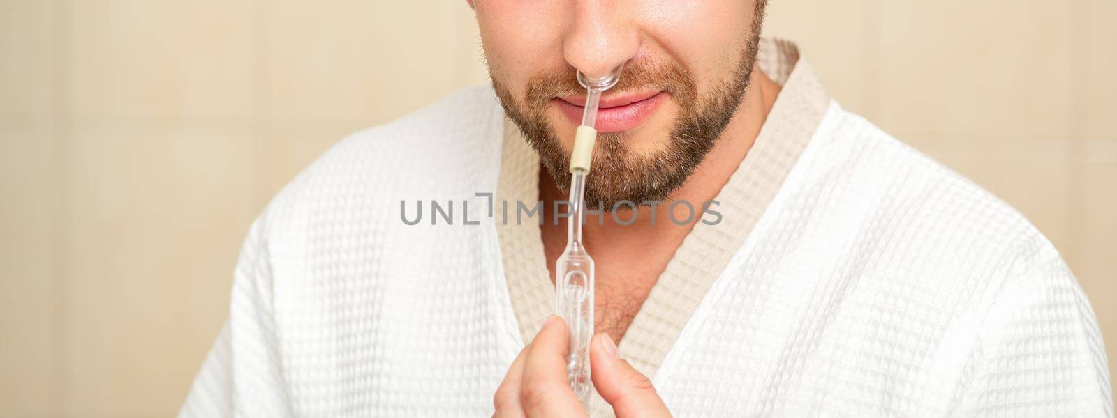 Young caucasian man receiving nasal inhalation Maholda with essential oil in the nose at a hospital