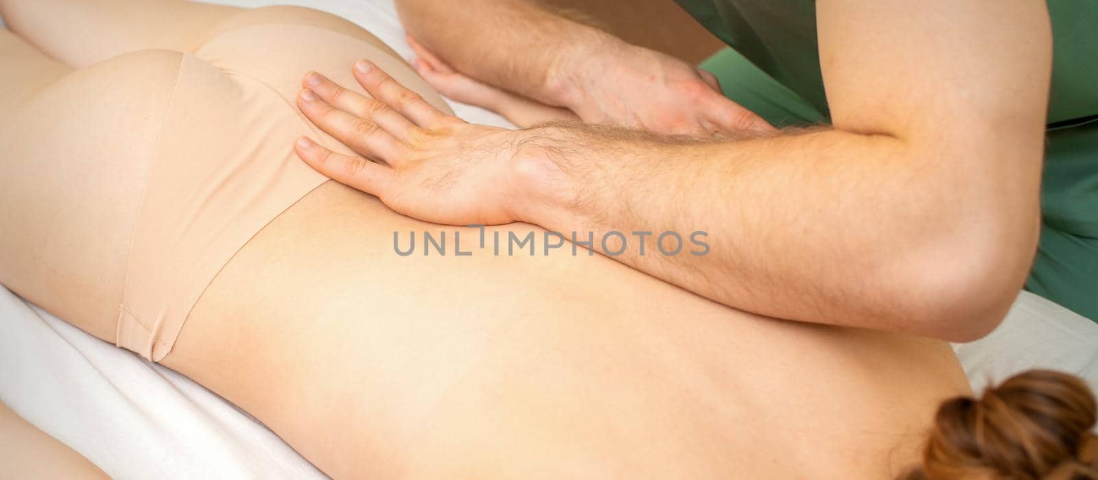 White woman receiving back massage by the hand of a masseur in spa