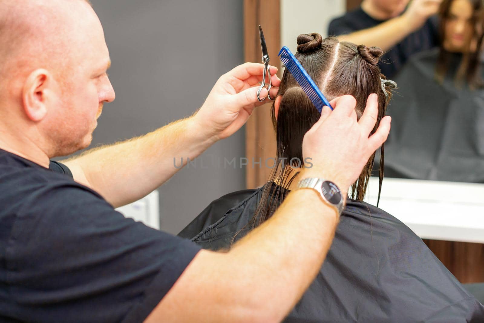 Male stylist cutting the hair of female client in professional beauty salon. by okskukuruza