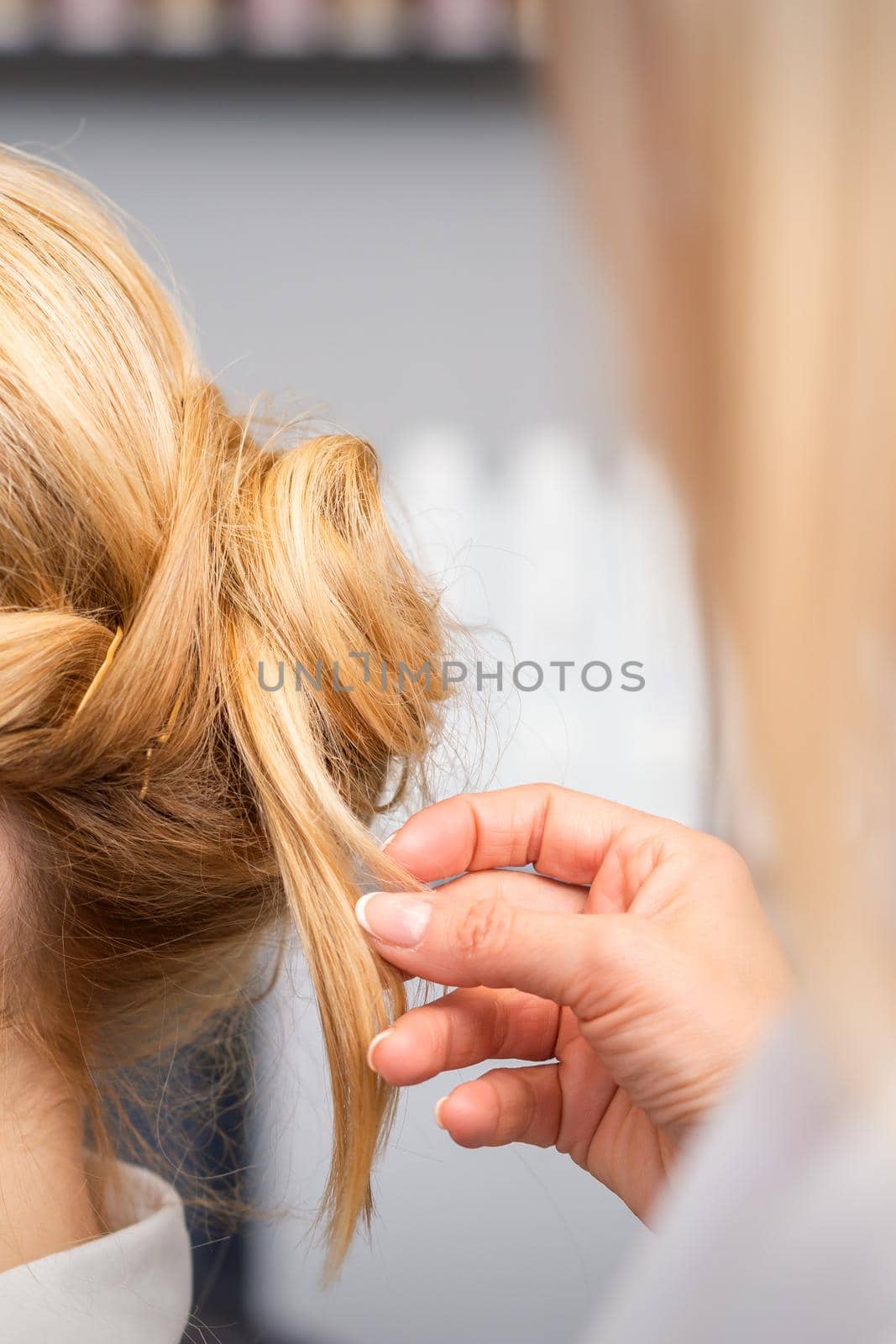 Close-up hairdresser styling blonde hair on the back of the head in a beauty salon