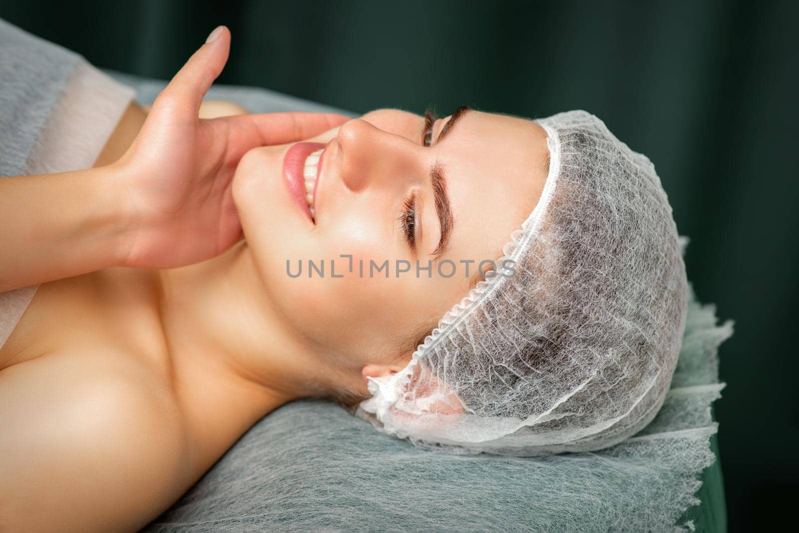 Doctor examining the beautiful face of young smiling woman in beauty clinic