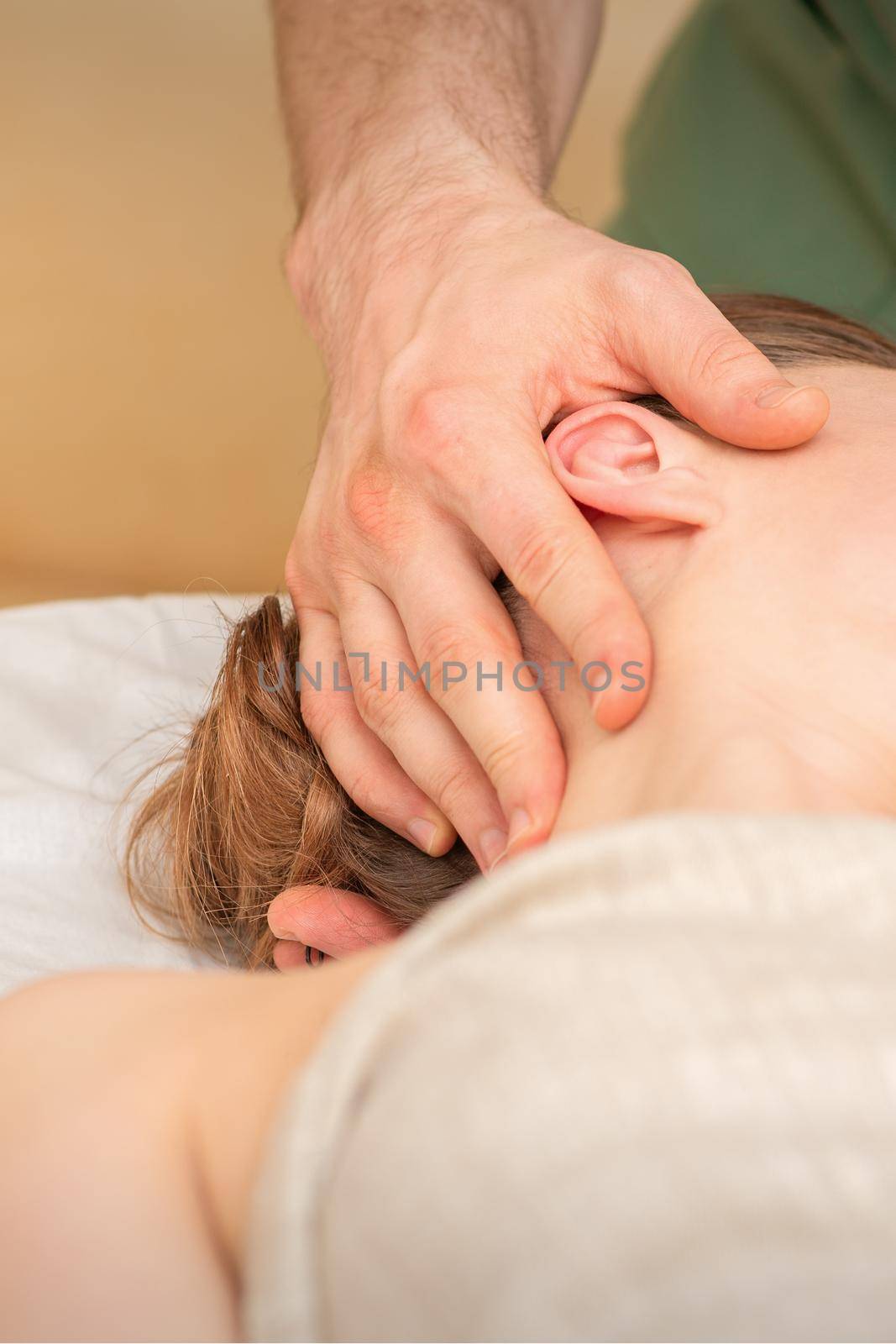 Osteopath doing massage on the female head in rehabilitation clinic center