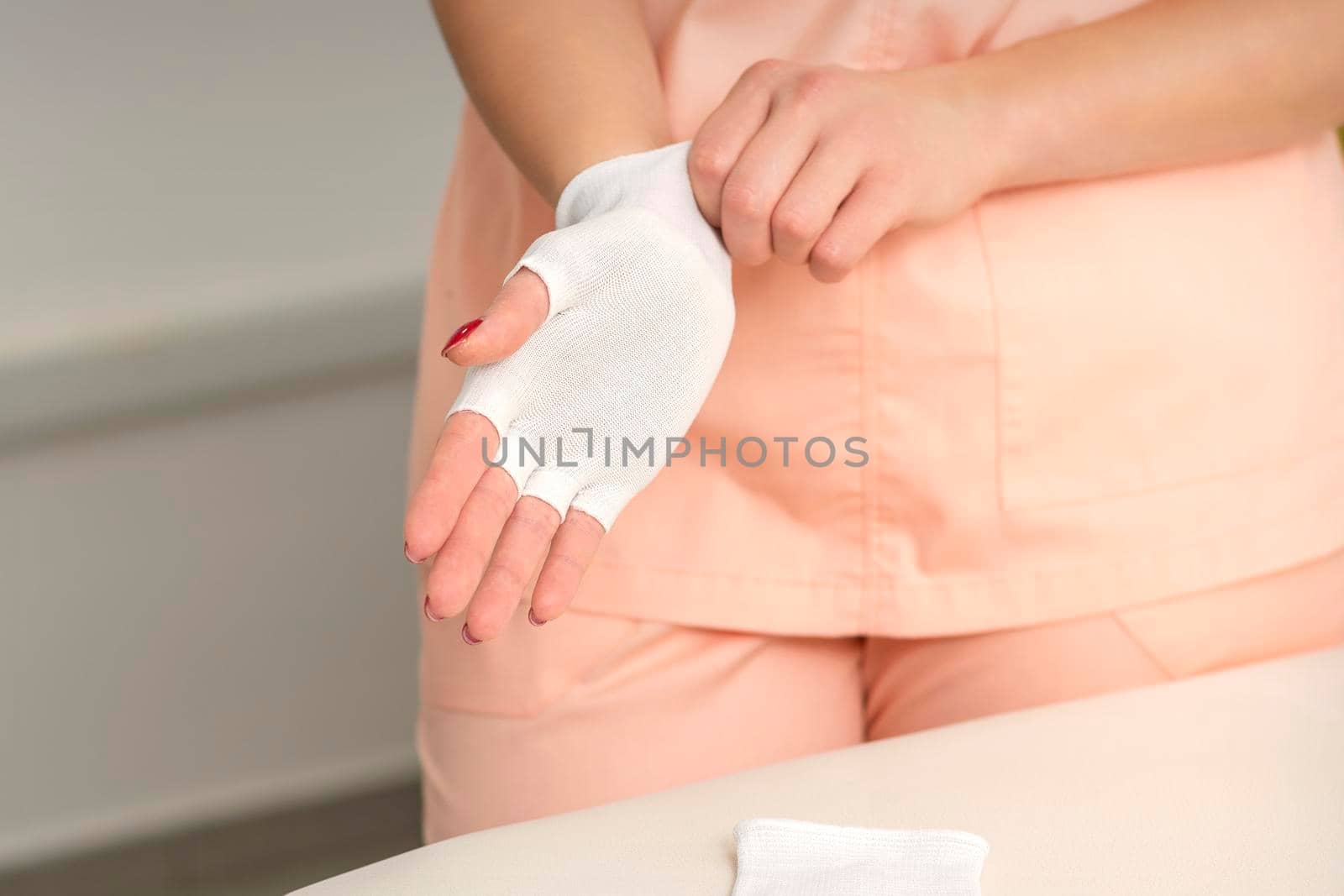 Cosmetologist in workwear wearing white bamboo fingerless gloves on her hands
