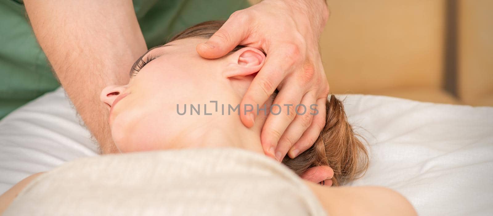 Osteopath doing massage on the female head in rehabilitation clinic center