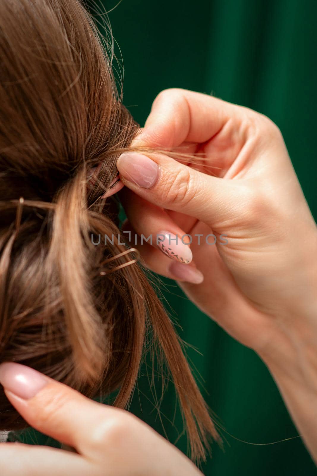 Hairdresser makes hairstyles for a young woman in beauty salon close up