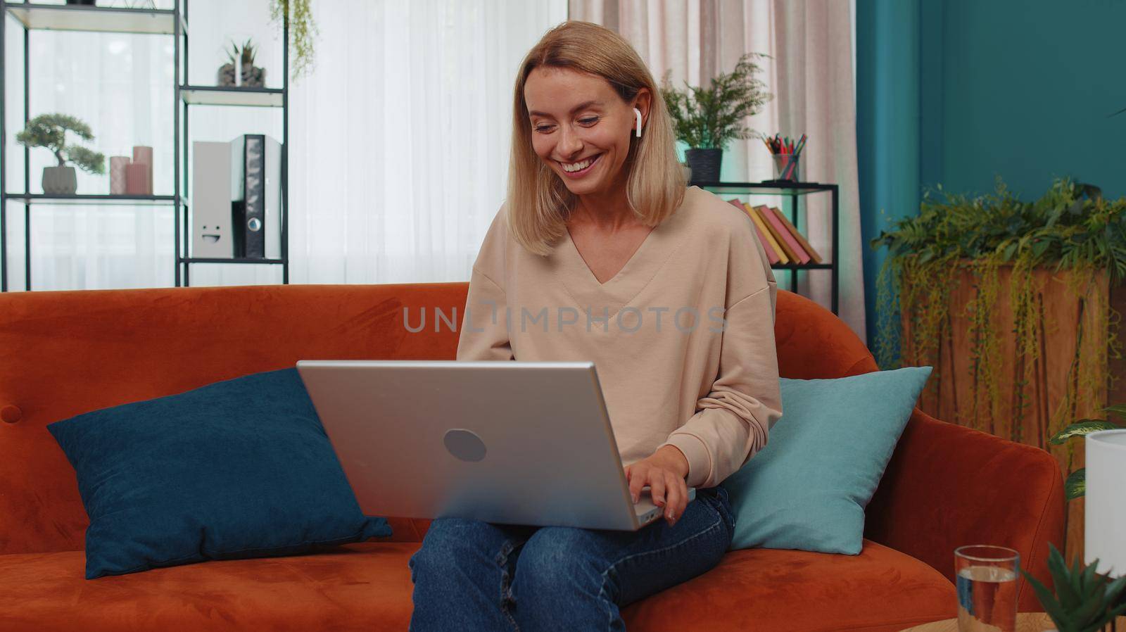 Woman sitting on home couch, looking at camera, making video conference call with friends or family by efuror