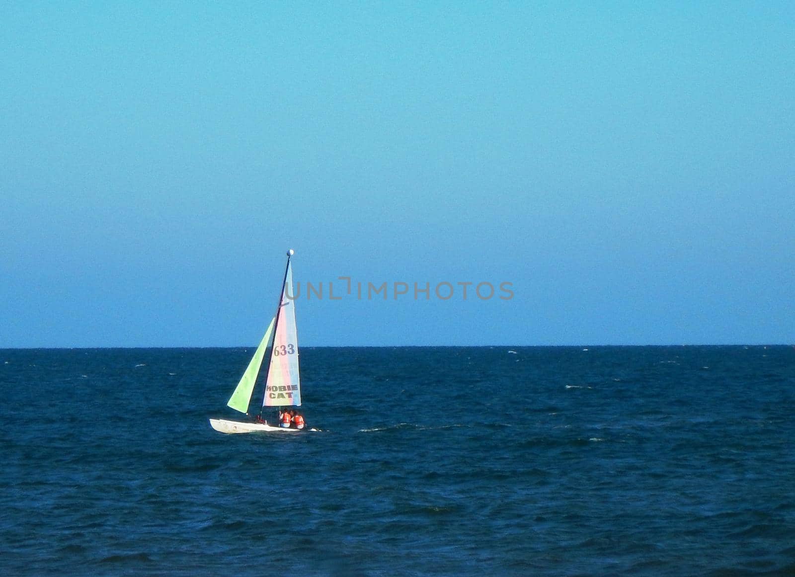 Sailboat in the blue sea with blue sky in the background
