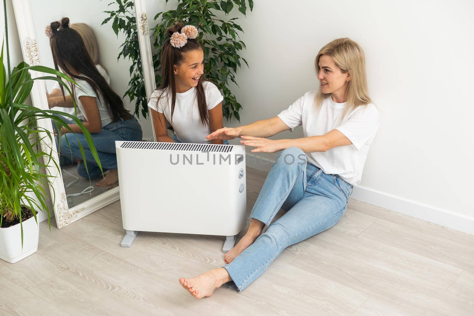 Cold home, freezing family, mother and daughter Sitting Near Heater.