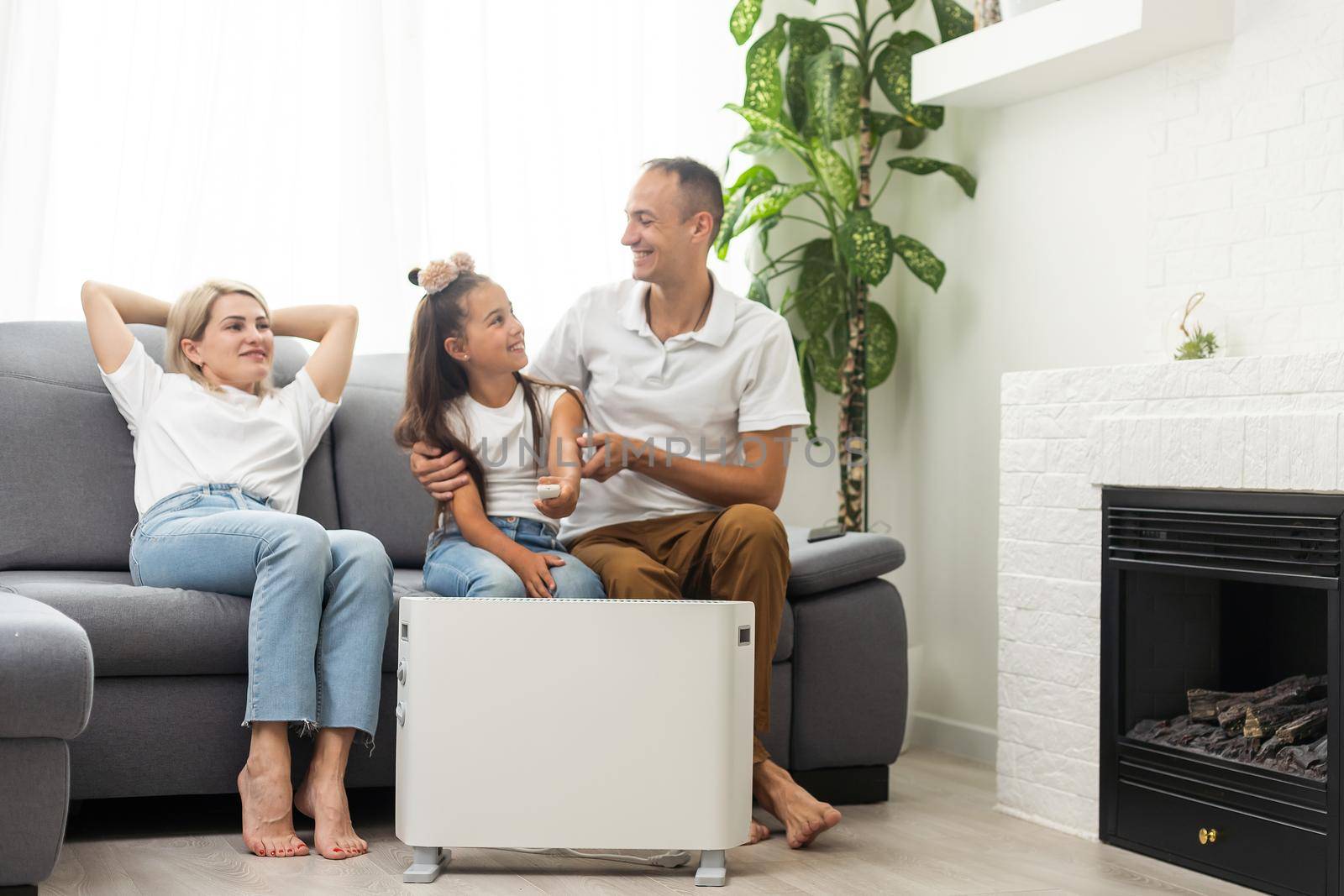 Electric heater at home. Young family warms his frozen hands near a heating radiator.