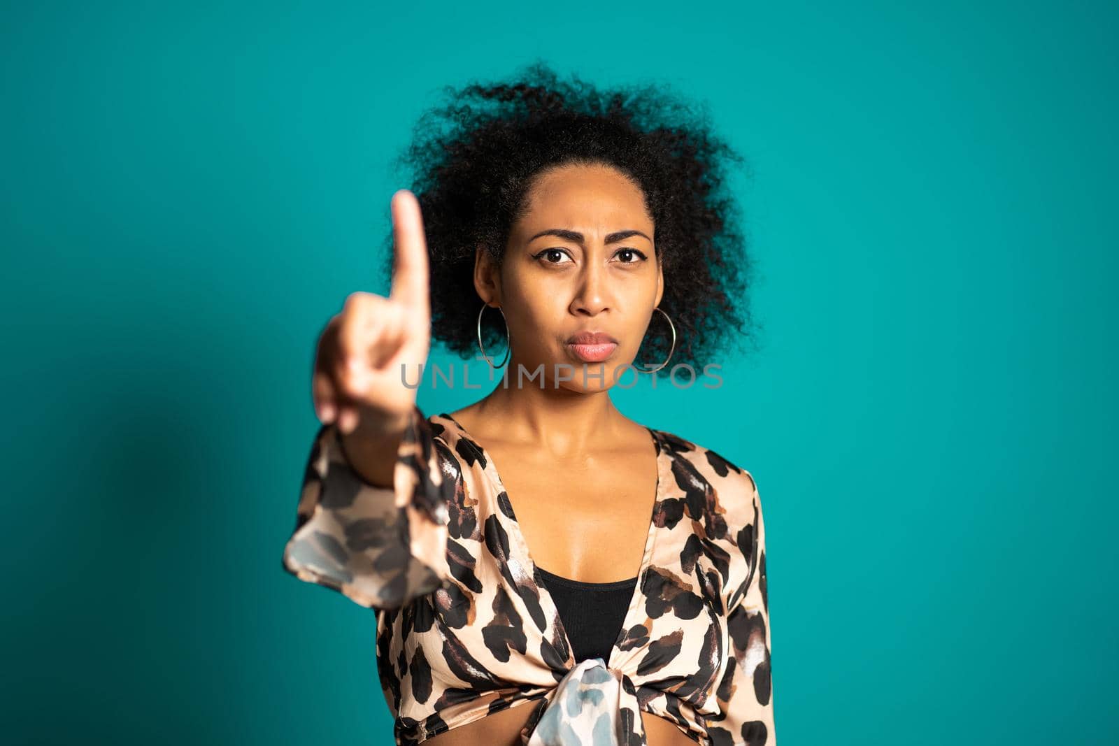 Mixed race woman disapproving with NO hand sign gesture. Denying, rejecting, disagree, portrait of beautiful girl on blue background. High quality photo