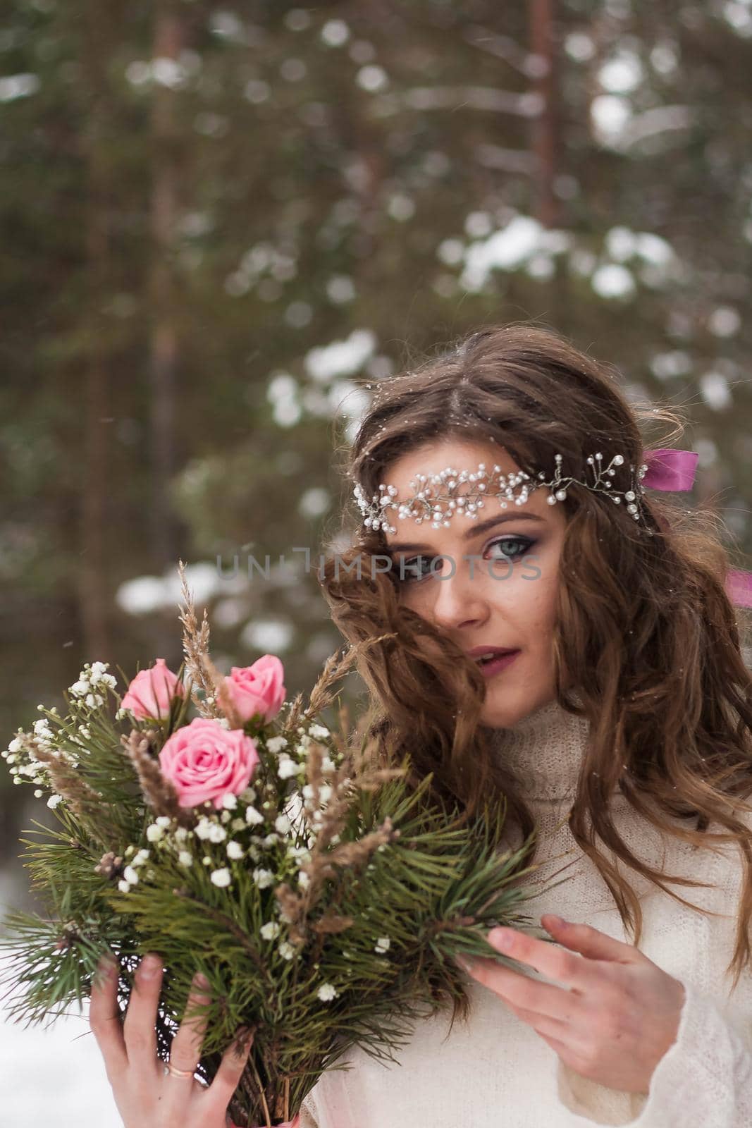 Beautiful bride in a white dress with a bouquet in a snow-covered winter forest. Portrait of the bride in nature.Beautiful bride in a white dress with a bouquet in a snow-covered winter forest. Portrait of the bride in nature.