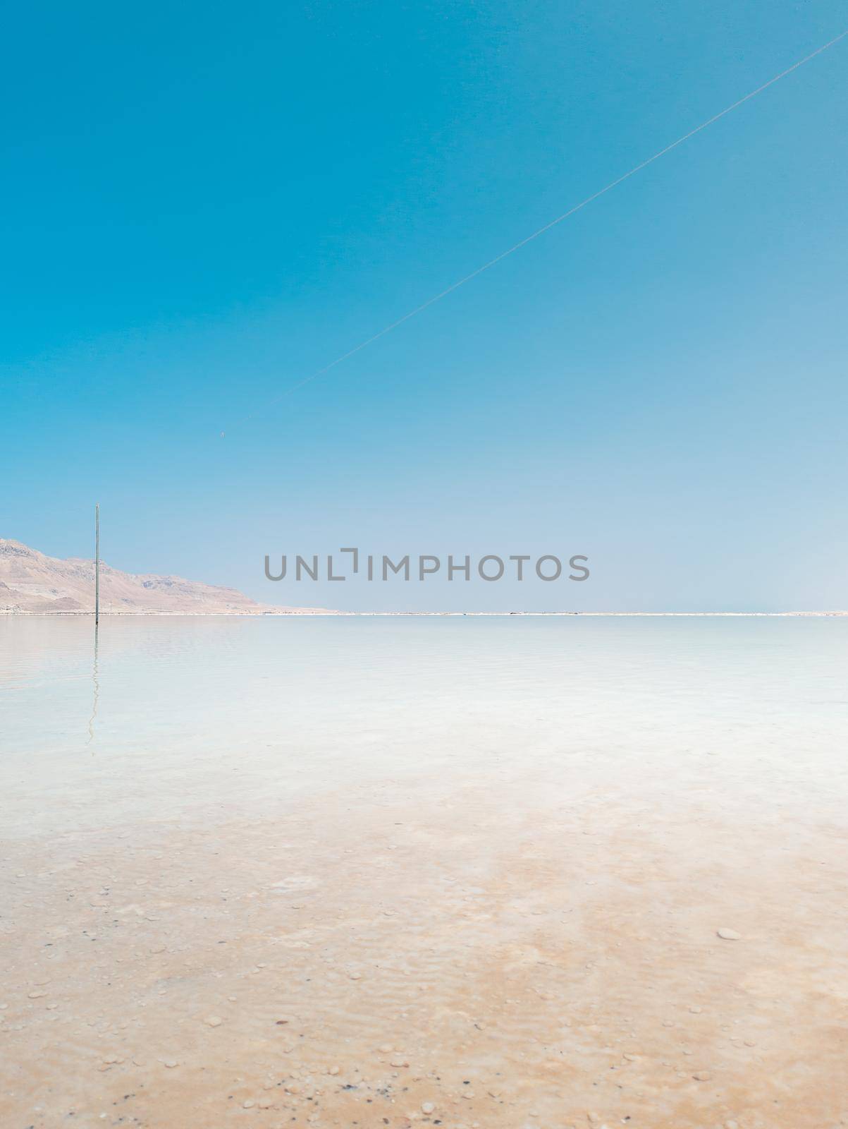 Landscape view on Dead Sea salt crystals formations, clear cyan green calm water at Ein Bokek beach, Israel