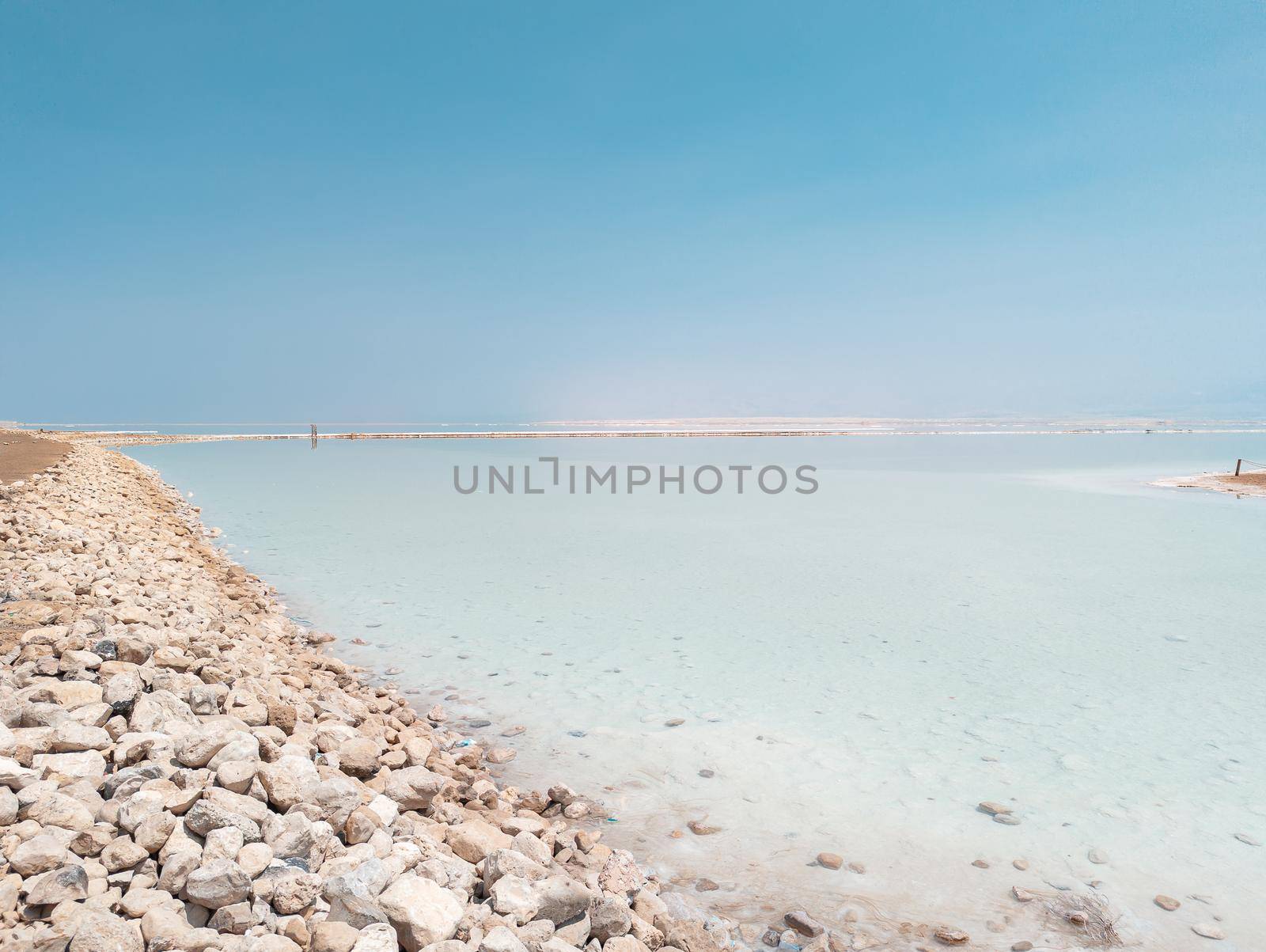 Landscape view on Dead Sea salt crystals formations, clear cyan green calm water at Ein Bokek beach, Israel