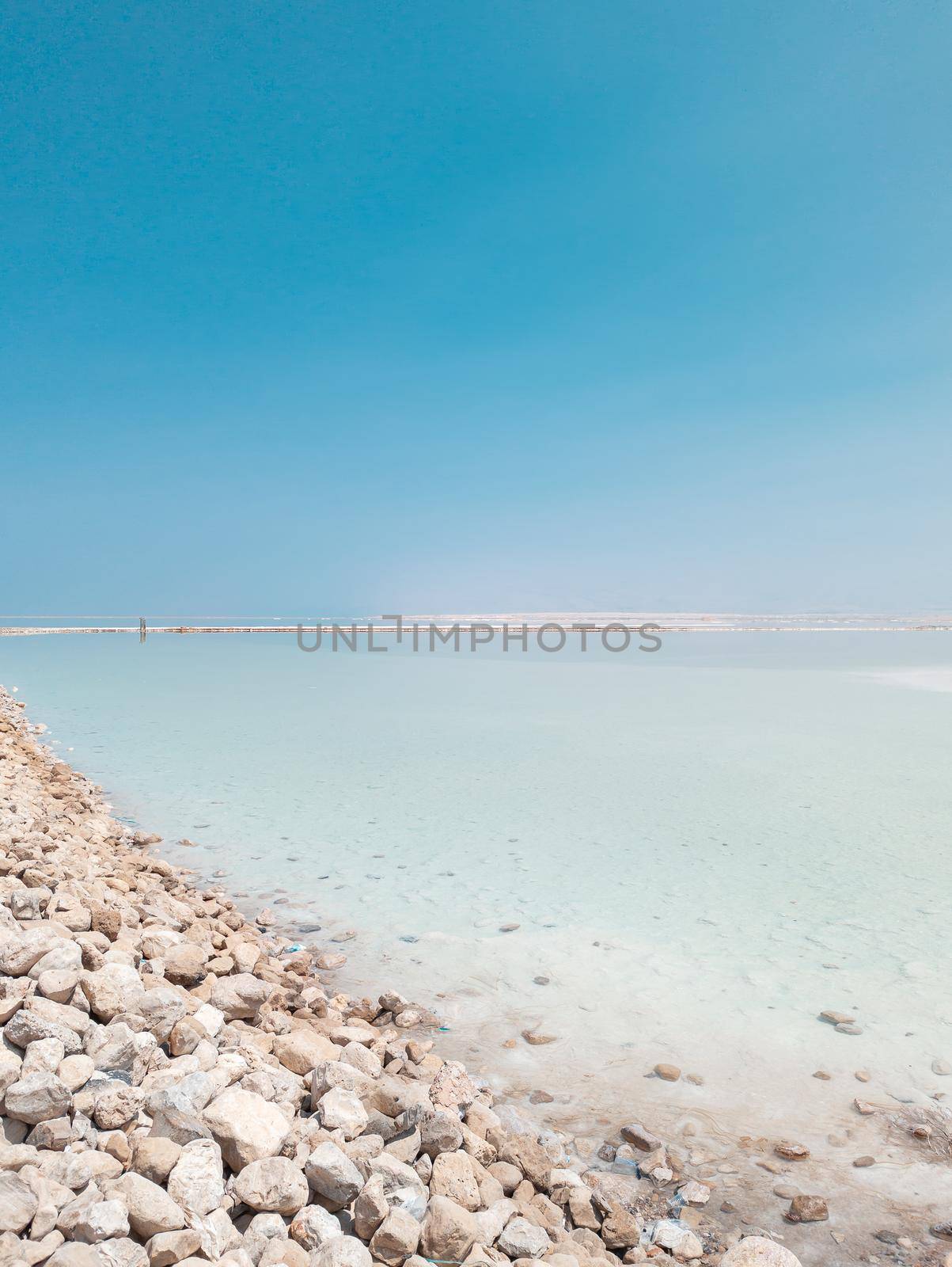 Landscape view on Dead Sea salt crystals formations, clear cyan green calm water at Ein Bokek beach, Israel